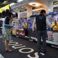 Focused: A woman is shown Sharp Corp. LCD televisions Tuesday at a store in Tokyo.  | AFP-JIJI