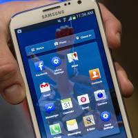 Going mobile: A Facebook Inc. employee holds a smartphone running the new Home program at the company\'s headquarters on April 4 as the social-networking pioneer tries to boost advertising sales on small screens. | BLOOMBERG