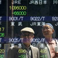 Meltdown: Pedestrians are reflected by a stock display outside a securities firm in Tokyo on Thursday, when the Topix index slid more than 5 percent as financial companies plunged amid rising bond yields. Bond vigilantes wake investors from voodoo 'Abenomics' trance