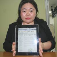 Yukie Yoshikawa, a fellow in the Okinawa regional security policy division, shows an English-language website she is developing at the prefectural office on Nov. 13. | AYAKO MIE