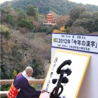 Golden year: Seihan Mori, chief monk of Kiyomizu Temple in Kyoto, writes the kanji for gold on a white screen Wednesday at the temple. The character was chosen by the public as best representing this year. | KYODO