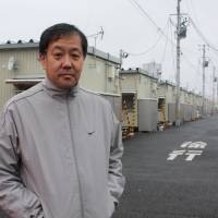 Masahiro Iitsuka stands outside the temporary housing complex he is staying at in Taihaku Ward, Sendai, where he also heads the residents association. | SETSUKO KAMIYA