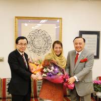 Saudi Arabian Ambassador Abdulaziz Turkistani (right), with Kazuyuki Hamada, then parliamentary vice minister for foreign affairs, congratulates Nobuko Sagawa (center), a Japanese specialist in Arabic calligraphy, at his embassy in Tokyo on Dec. 20. | EMBASSY OF SAUDI ARABIA