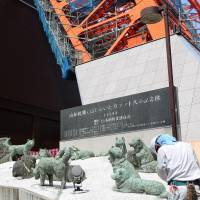 New home: A construction worker removes the statues of the Sakhalin huskies that accompanied the first Japanese Antarctic expedition team, in the late 1950s, from the base of Tokyo Tower on Wednesday. | KYODO