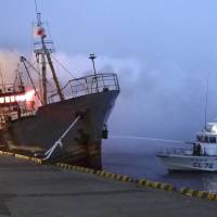 Gutted: A Japan Coast Guard vessel uses its water cannon as flames pour from the bridge of the 497-ton Cambodia-registered freighter Taigan early Thursday in Wakkanai port in Hokkaido. | JAPAN COAST GUARD/KYODO