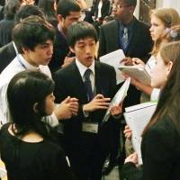 Give and take: A Japanese student (center), playing the role of a diplomat, negotiates with other students during a mock U.N. meeting Saturday in New York. | KYODO