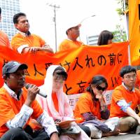 Staying put: Foreigners without proper visas, along with families and supporters, continue a sit-in outside the Tokyo Regional Immigration Bureau in Minato Ward on Tuesday. They plan a five-day protest. Visa violators continue sit-in at Immigration