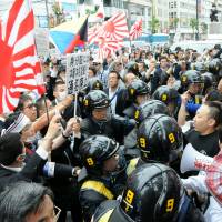 Provocateurs: Riot police prevent an anti-Korean group (at left) and Korean residents and their supporters from clashing Sunday in the Shin-Okubo district in Tokyo. Nationalism rearing ugly head with greater frequency
