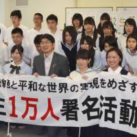 A million strong: Nagasaki Mayor Tomihisa Taue holds up a banner with high school students who are aiming to collect 1 million signatures calling for the abolition of nuclear weapons at the Nagasaki Atomic Bomb Museum on Sunday. | KYODO