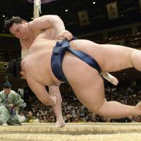 Crash landing: Harumafuji (rear) throws Goeido at the Summer Grand Sumo Tournament on Monday. | KYODO