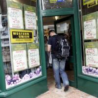 A new life, a new land: An immigrant walks past job adverts in the window of a news agent in west London in this 2006 photo. The adverts are in both Polish and broken English. One study found that neighborhoods that have a high level of immigrants report a lower number of offenses for some crime categories. | BLOOMBERG