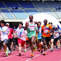 Ordinary citizens join Kenyan athletes Daniel Njenga (center), the 2007  Tokyo Marathon champion, and former marathon world record holder Eric  Wainaina at the start of a charity race Saturday at Nissan Stadium in  Yokohama. Teams of up to 20 runners competed to see who could go the farthest in four hours, seven minutes and 16 seconds &#8212; double the marathon world record time. The event, \"Run for Africa 2013,\" was held on the sidelines of the TICAD V African aid conference. | COURTESY OF MUDEF