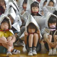 Children at Sendai\'s Katahiracho Elementary School wear protective outfits during a disaster drill staged  Wednesday to mark the 35th anniversary of a 7.4-magnitude earthquake off Miyagi Prefecture that caused major damage to the city. | KYODO
