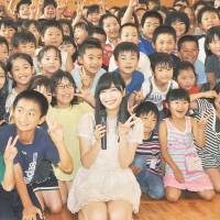 AKB48 member Rino Sashihara, who won the all-female idol group\'s popularity contest June 8, poses with elementary school students Friday in her hometown of Oita, where she serves as the tourism ambassador. | KYODO
