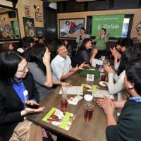 Trivia pursuit: People take part in a pub quiz organized by Oxfam Japan at the FooTNiK pub in Ebisu, Shibuya Ward, Tokyo, on Feb. 16. Participants pay 1,000, which goes to the international aid organization. | YOSHIAKI MIURA PHOTOS