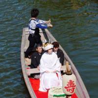 Life\'s journey: A make-believe bride and her groom glide in traditional style down the Mae River in Itako to the delight of visitors. | COURTESY OF HARADA TOMATO