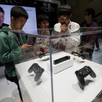 Making a splash: Attendees look at Sony\'s new Playstation 4 controller during Game Developers Conference 2013 in San Francisco on March 27. | BLOOMBERG