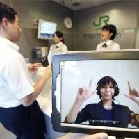Sign of the times: A JR East operator uses sign language Monday on an iPad screen in Shinagawa Station as the railway began testing a new service for the hearing-impaired. | KYODO