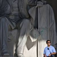 Dastardly act: A U.S. police officer stands guard at the Lincoln Memorial in Washington on Friday after a vandal splattered green paint on the statue and the floor area. | AP