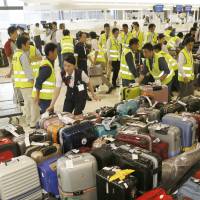 Narita airport staff round up checked luggage Thursday after computer glitches disrupted the airport\'s explosives detection system and another system at immigration control. The glitches created a line about 600 people long in the departures lobby. | KYODO