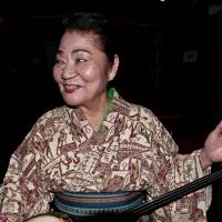 Keeping it real: Misako Oshiro tunes up her sanshin after an impromptu decision to play at her minyo (folk song) club Shima Umui in Naha, Okinawa Prefecture.  | STEPHEN MANSFIELD