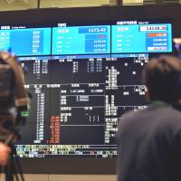Going public: TV crews film a board flashing the numbers of Suntory Beverage &amp; Food\'s listing Wednesday on the Tokyo Stock Exchange. | AFP-JIJI