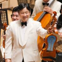 No ordinary driftwood: Crown Prince Naruhito displays a viola Sunday at a concert held by Gakushuin University alumni in Tokyo. The viola was partially built from a pine tree hit by the March 2011 tsunami in Rikuzentakata, Iwate Prefecture. | POOL