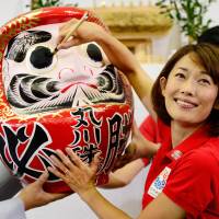 Dream come true: Liberal Democratic Party candidate Tamayo Marukawa dots the eyes of a \"daruma\" doll in Tokyo on Sunday after winning a seat in the Upper House election. | AFP-JIJI
