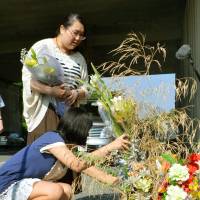Roadside memorial: Ayano Hayashi (standing) mourns her mother Tuesday at the site of the April 2012 bus crash on the Kan-Etsu Expressway in Fujioka, Gunma Prefecture, that took her life. | KYODO