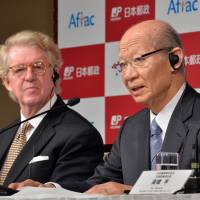 Deal assured: Japan Post President Taizo Nishimuro addresses reporters Friday while Daniel Amos, chairman of U.S. insurance giant American Family Life Assurance Co., looks on as they announce their agreement in Tokyo. | BLOOMBERG