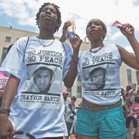 Rallying to the cause: Tanisha Rollins, 29, of Dallas, and 32-year-old Nicole Cowan of Oxon Hill, Maryland, join a \"Justice for Trayvon\" vigil on Saturday to protest the shooter\'s acquittal in the death of black teen Trayvon Martin, in front of the historic E. Barrett Prettyman Federal Courthouse in Washington.  | THE WASHINGTON POST