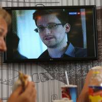 Phantom: Passengers eat in Moscow\'s Sheremetyevo airport June 26 as Russian TV news reports on Edward Snowden. | AP