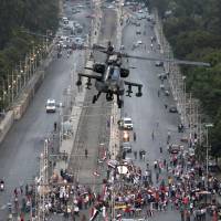 Ready to swoop: An attack helicopter flies over a street near the presidential palace in Cairo on Friday. A top Muslim Brotherhood leader, Mohammed Badie, has vowed to restore ousted President Mohammed Morsi to office, saying Egyptians will not accept \"military rule\" for another day. | AP
