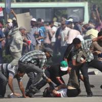 Casualty of unrest: Supporters of ousted Egyptian President Mohammed Morsi help carry a man who was shot near the Republican Guard building in Cairo on Friday. | AP