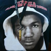 Image of power: A single bullet dangles on a ribbon over a Trayvon T-shirt being worn by a participant at a rally in Los Angeles on Monday. Starkly different outcomes in Florida gun cases