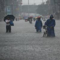 Our fault?: Residents wade through a street in Manila on Tuesday. A new U.N. draft report concludes there is a 95 percent certainty that human activity is responsible for most global warming. | AFP-JIJI