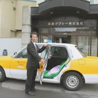 A Hakodate Taxi Ltd. cabby shows off a special seat for pregnant women nearing labor Thursday in Hakodate, Hokkaido, as part of the carrier\'s new \"jintsu\" (labor-pain) taxi service, which expectant mothers can reserve. | KYODO