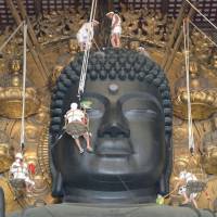 Monks at Todaiji Temple dust and wipe clean the 15-meter Great Buddha statue in the city of Nara on Wednesday. It took about 150 monks to clean up the statue. | KYODO