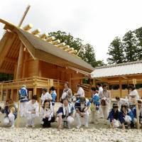 Local residents place fist-sized white stones in the compound of Ise Shrine in Mie Prefecture on Saturday as part of renovation work currently being carried out at the renowned Shinto site. | KYODO