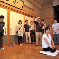 Storyteller for a day: A \"traveler\" taking part in a \"rakugo\" job experience program sits on the stage at Asakusa Engei Hall in Tokyo on Aug. 3. | YOSHIAKI MIURA