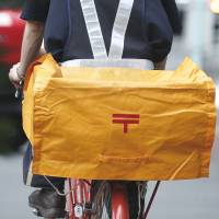 Special delivery: A Japan Post Co. mailman cycles on a street near one of the company\'s branches in Tokyo in mid-June. | BLOOMBERG