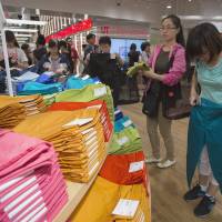 Sizing them up: Customers shop for pants at the opening of Fast Retailing Co.\'s Uniqlo Lee Theatre flagship store in Hong Kong on April 26. Uniqlo said it will open its biggest flagship anywhere in Shanghai on Sept. 30. | BLOOMBERG