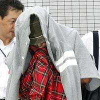 Under cover: Tomoya Ikeda, one of two men arrested Monday over an investment scheme, is escorted by an investigator to a police station in Ichinomiya, Aichi Prefecture. | KYODO PHOTO