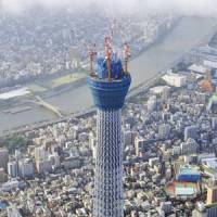 Bright lights, big city: Tokyo Sky Tree, still under construction, stretches 408 meters into the sky in late July. It will be illuminated for three hours next week. | KYODO PHOTO