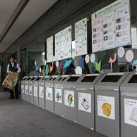 Keeping them honest: Volunteers at the COP10 biodiversity meeting keep track of the use of trash bins for separating garbage at the Nagoya Congress Center. | SETSUKO KAMIYA