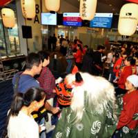 One for the road: A traditional Japanese lion dancer attempts to bite a passenger to wish her a safe flight at Cathay Pacific\'s boarding gate at Haneda airport on Sunday. | YOSHIAKI MIURA PHOTO