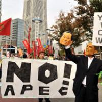 No disguising the message: A man wearing a Barack Obama rubber mask holds up a mask of Prime Minister Naoto Kan at an anti-APEC rally in Yokohama on Saturday. | YOSHIAKI MIURA PHOTO