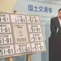 Stamped: Transport minister Akihiro Ota introduces license plates bearing 10 of the new issuing offices at a Friday press conference in Tokyo. | KYODO