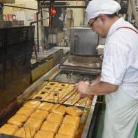 Top item: Kazuhiro Kishida cooks up some deep-fried tofu in the city of Fukui in July. | KYODO