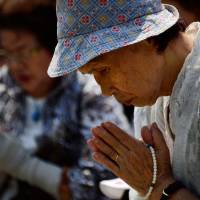 Prayers for peace: Elderly women pray for victims of the 1945 atomic bombing in front of the cenotaph at Peace Memorial Park in Hiroshima on Tuesday as ceremonies are held to mark the 68th anniversary of the bombing. | AFP-JIJI